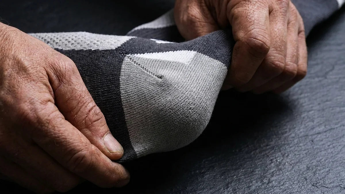 Tradesperson's hands inspecting ShiftForce™ reinforced heel zone, showing construction quality